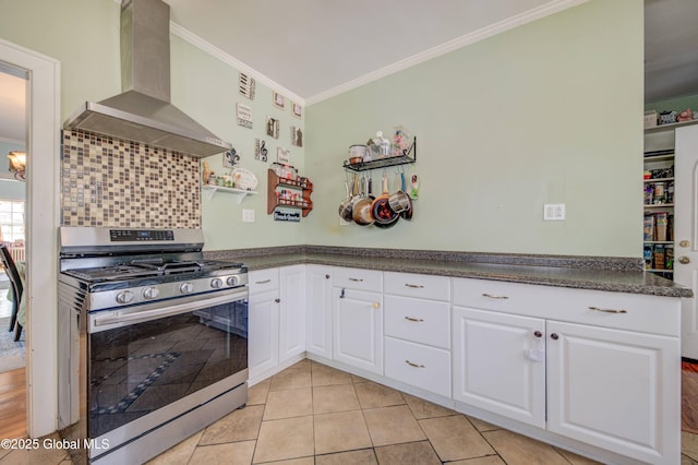 kitchen featuring wall chimney range hood, crown molding, white cabinets, dark countertops, and gas stove