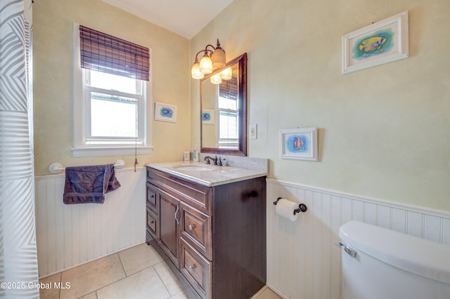 bathroom with toilet, tile patterned flooring, wainscoting, and vanity