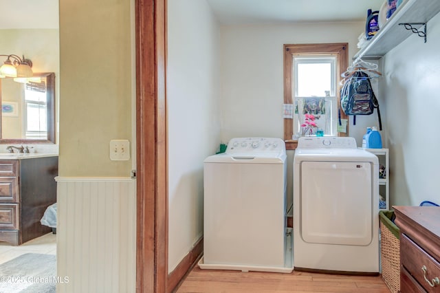 clothes washing area featuring washer and dryer, light wood-style flooring, laundry area, and a sink