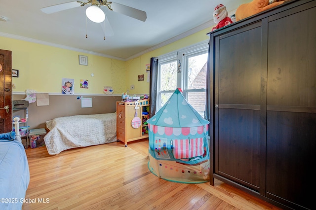 bedroom featuring ornamental molding, a ceiling fan, and light wood-style flooring