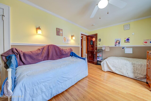 bedroom featuring crown molding, a ceiling fan, and wood finished floors