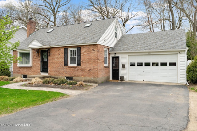 view of front of property with a shingled roof, an attached garage, brick siding, a chimney, and driveway