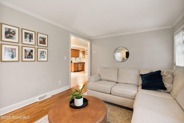 living area with crown molding, baseboards, visible vents, and light wood-type flooring