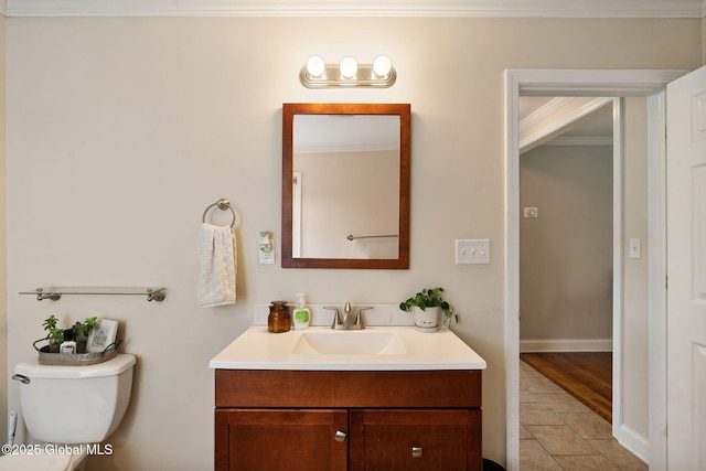 half bathroom featuring crown molding, vanity, toilet, tile patterned floors, and baseboards