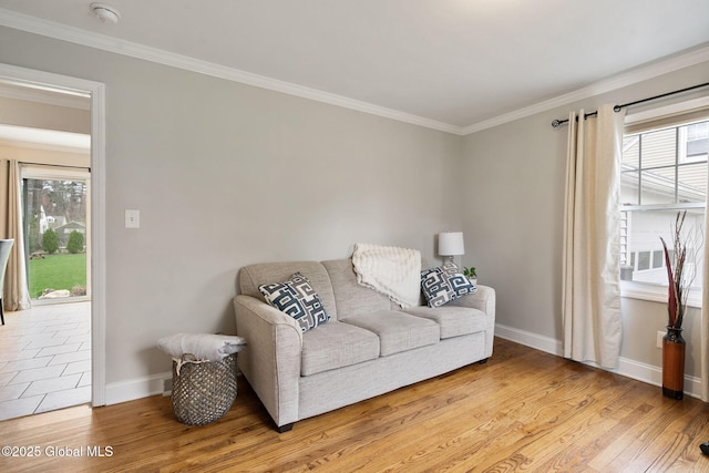 living room featuring baseboards, ornamental molding, a healthy amount of sunlight, and light wood-style flooring
