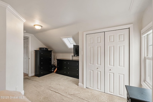 unfurnished bedroom featuring carpet floors, baseboards, vaulted ceiling with skylight, and a closet