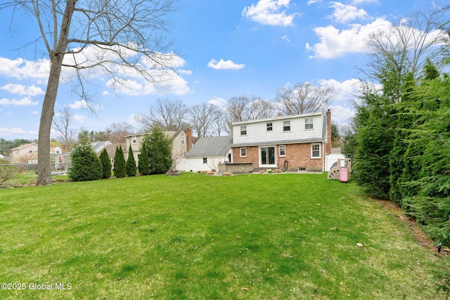 back of house featuring entry steps, a chimney, a yard, and brick siding