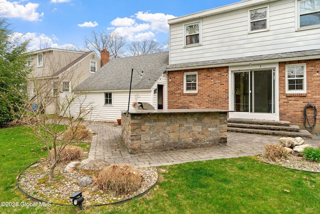 rear view of property with an outdoor kitchen, brick siding, a patio area, entry steps, and a yard