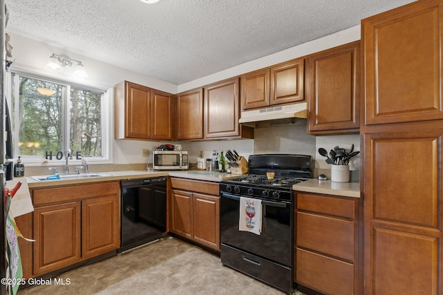 kitchen with a sink, brown cabinetry, black appliances, and under cabinet range hood