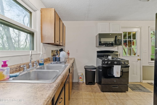 kitchen with light countertops, baseboards, a sink, and black appliances