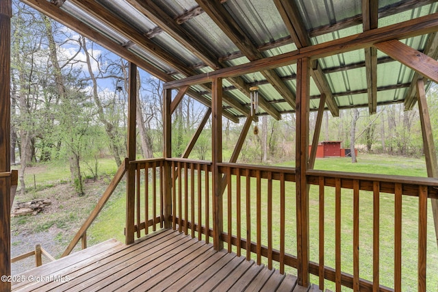wooden terrace featuring a lawn, a storage unit, and an outbuilding