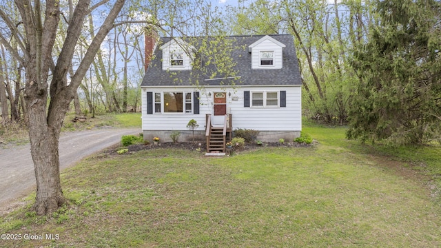 new england style home with roof with shingles, a chimney, and a front yard