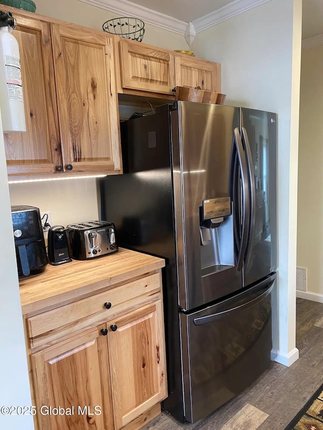 kitchen featuring butcher block counters, stainless steel fridge, visible vents, ornamental molding, and wood finished floors