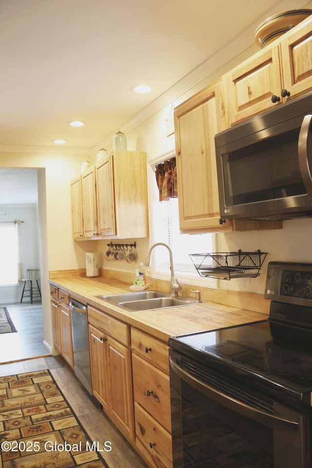 kitchen featuring a sink, appliances with stainless steel finishes, light brown cabinets, butcher block counters, and ornamental molding