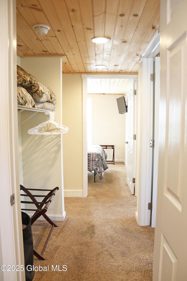 hallway with carpet, baseboards, and wooden ceiling
