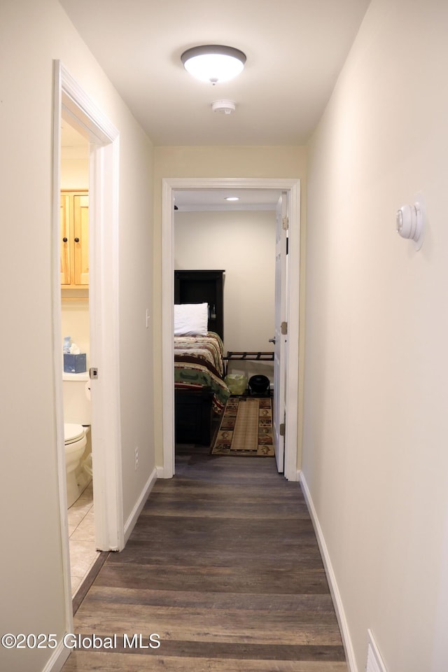 corridor featuring baseboards and wood finished floors