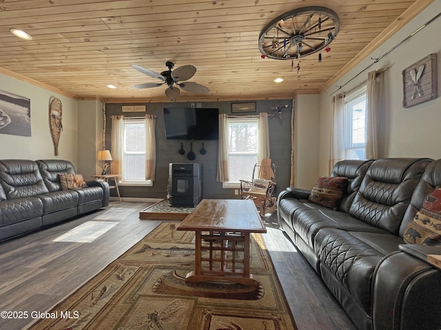 living area with wooden ceiling, wood finished floors, ceiling fan, a wood stove, and crown molding