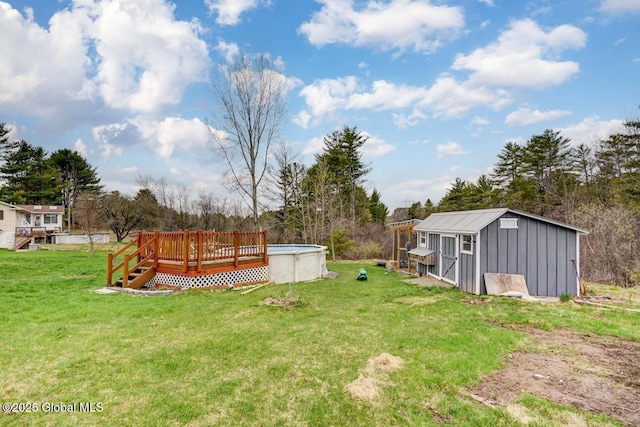 view of yard featuring an outdoor pool, a wooden deck, and an outbuilding