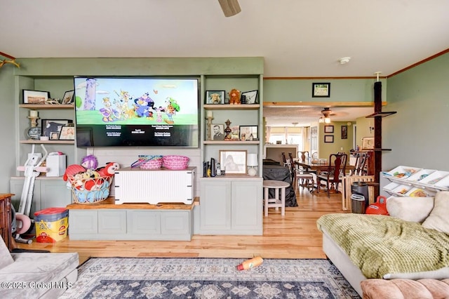 living area with ceiling fan, ornamental molding, and wood finished floors