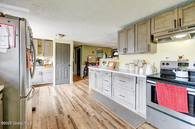 kitchen with a textured ceiling, stainless steel appliances, light wood-style flooring, and under cabinet range hood