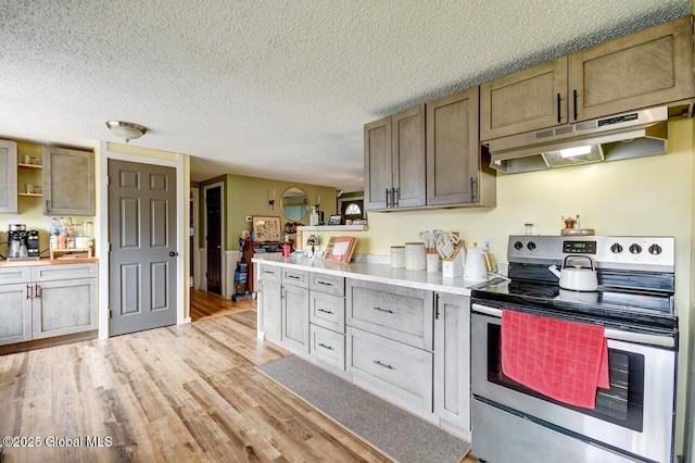 kitchen with a textured ceiling, stainless steel range with electric stovetop, light countertops, light wood finished floors, and under cabinet range hood