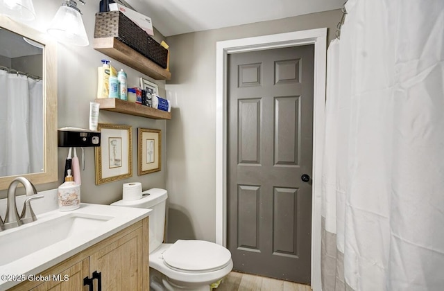 bathroom with toilet, wood finished floors, and vanity