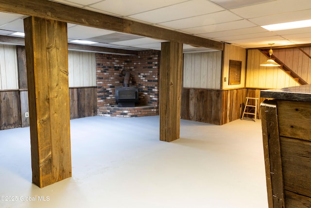 19 Centennial Dr, Queensbury, NY 12804 - finished basement with wooden walls, a wood stove, a paneled ceiling, and stairs