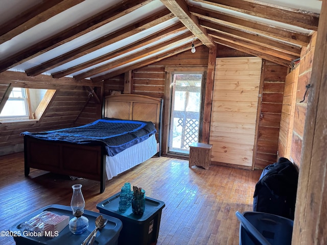 bedroom featuring wood walls, multiple windows, lofted ceiling, and wood-type flooring