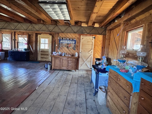 miscellaneous room with beam ceiling, wood walls, and wood-type flooring