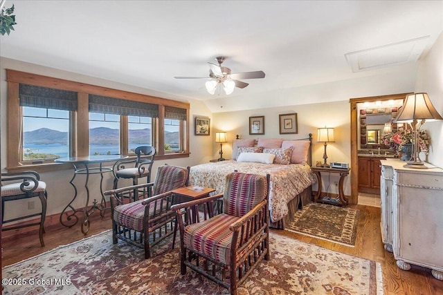 bedroom featuring light wood-style flooring, attic access, a mountain view, and multiple windows