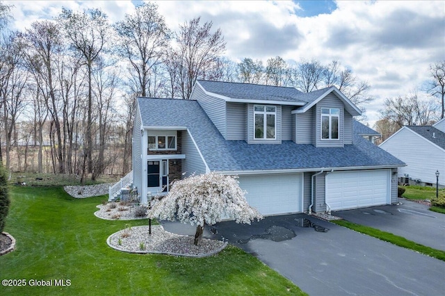 view of front of house with an attached garage, driveway, roof with shingles, and a front lawn