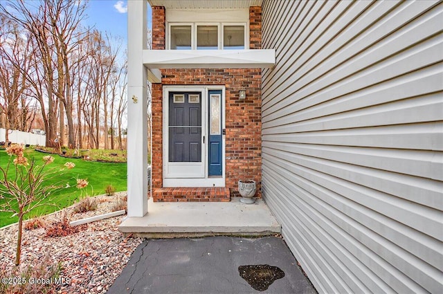 entrance to property with a yard and brick siding