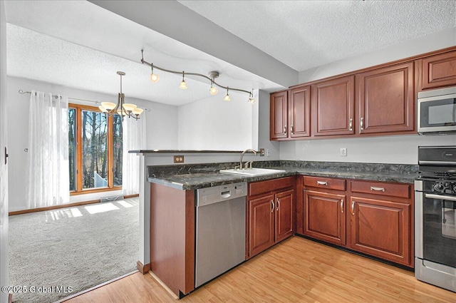 kitchen featuring appliances with stainless steel finishes, an inviting chandelier, a sink, a textured ceiling, and light wood-style flooring