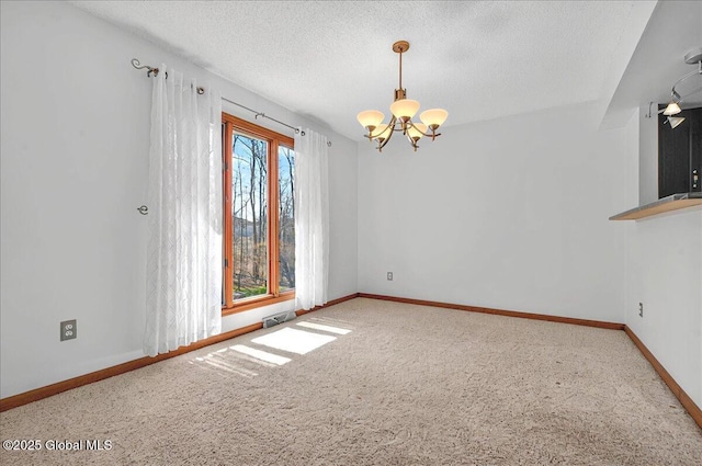 carpeted empty room with a textured ceiling, an inviting chandelier, and baseboards