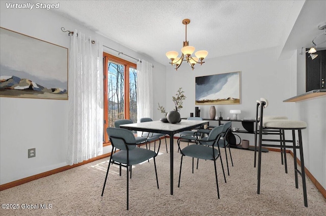 dining area featuring carpet flooring, a textured ceiling, baseboards, and a notable chandelier
