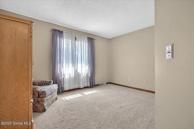 unfurnished room with baseboards, carpet flooring, a textured ceiling, and visible vents