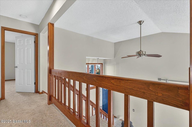 corridor with carpet floors, lofted ceiling, baseboards, a textured ceiling, and an upstairs landing