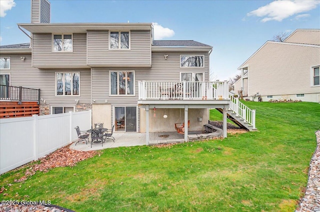 back of property with a lawn, a deck, a patio area, stairway, and fence