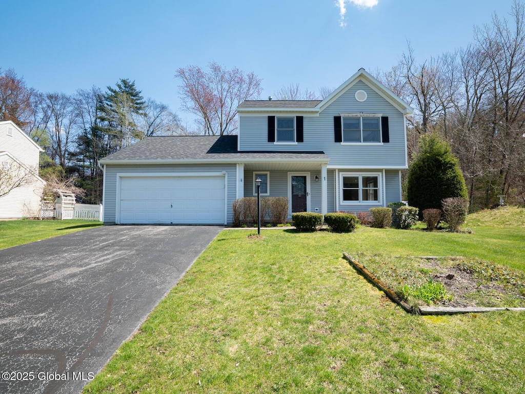 traditional home featuring a front yard, driveway, and an attached garage