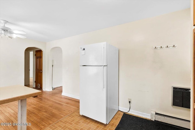 kitchen featuring ceiling fan, arched walkways, freestanding refrigerator, heating unit, and a baseboard radiator