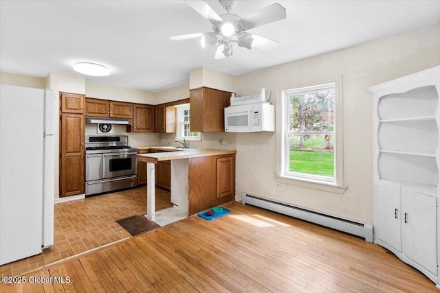 kitchen with brown cabinetry, white appliances, light countertops, under cabinet range hood, and a baseboard heating unit