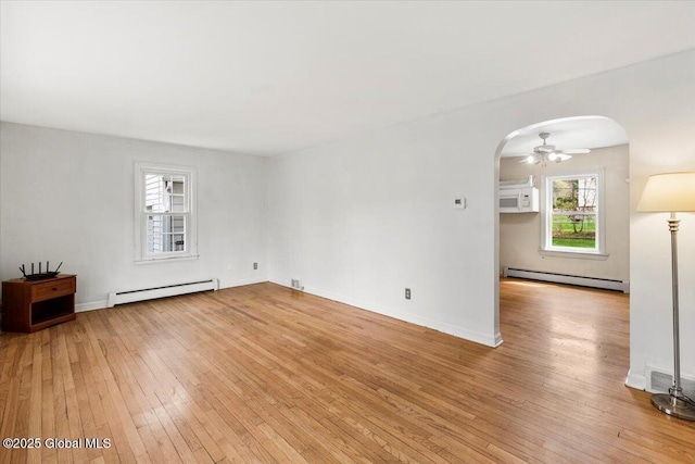 unfurnished living room featuring arched walkways, a baseboard radiator, baseboard heating, and light wood finished floors