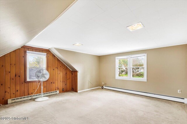 additional living space featuring a baseboard radiator, carpet, lofted ceiling, and wood walls