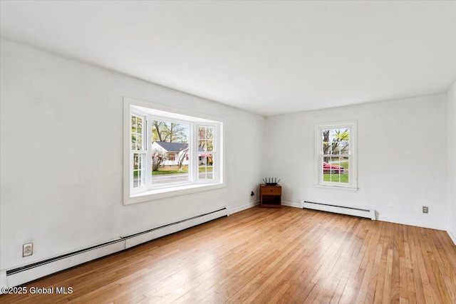unfurnished room with a healthy amount of sunlight, baseboard heating, and hardwood / wood-style flooring