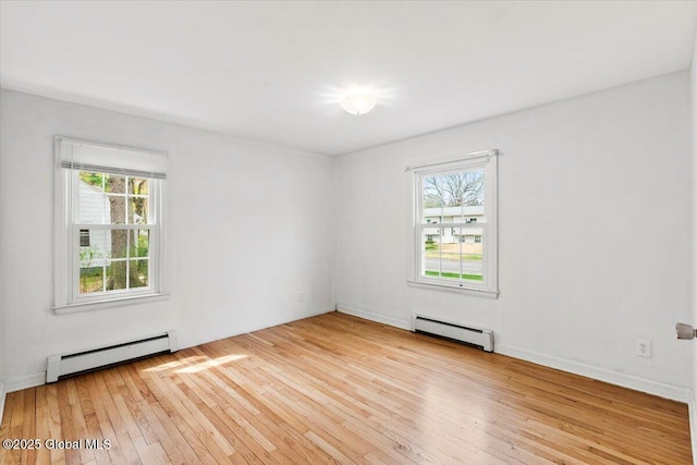spare room featuring a baseboard heating unit, a wealth of natural light, and hardwood / wood-style floors