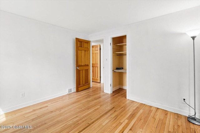 unfurnished bedroom featuring visible vents, light wood finished floors, baseboards, and a closet