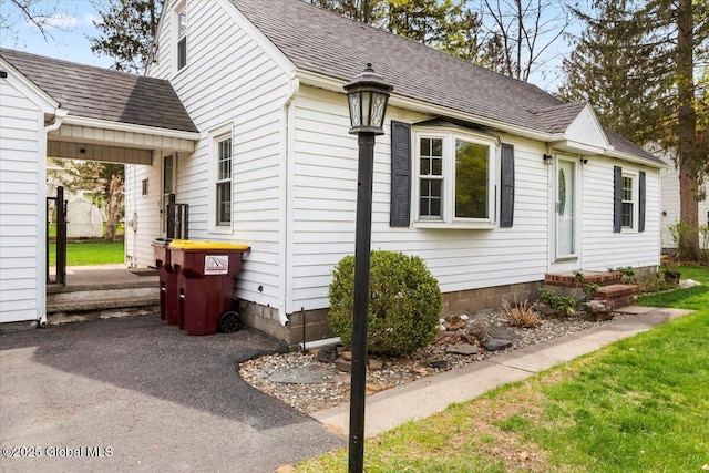 view of side of property with a lawn and a shingled roof