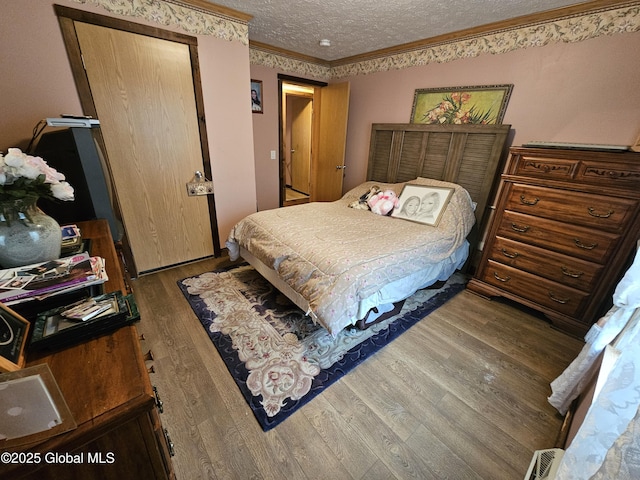 bedroom with crown molding, a textured ceiling, and wood finished floors