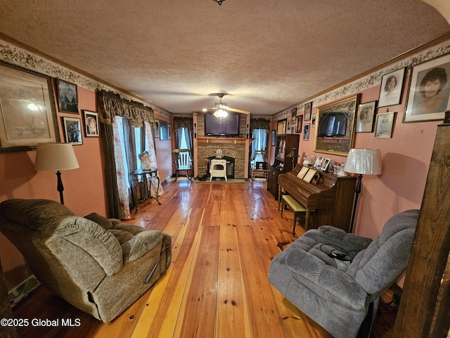 living room with crown molding, a textured ceiling, a ceiling fan, and light wood-style floors