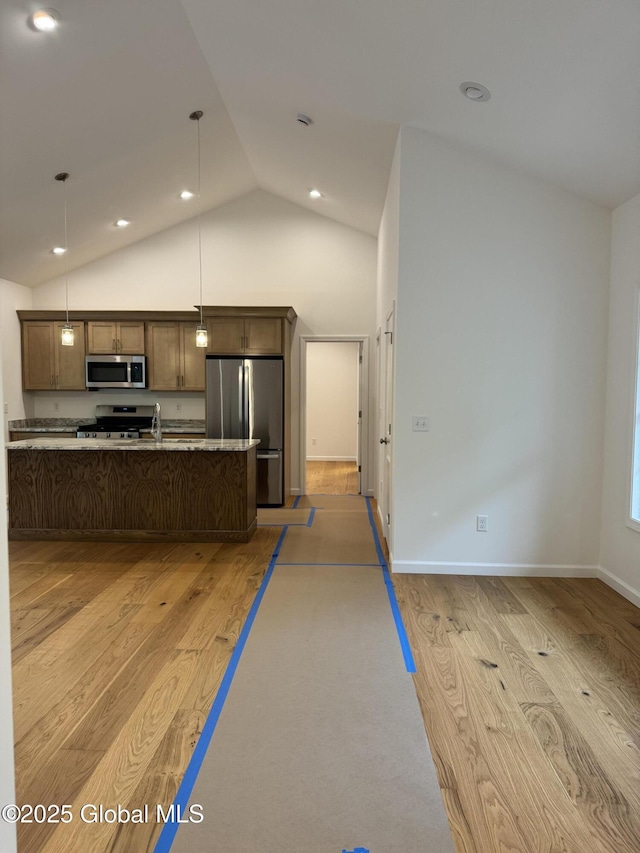 2 Birch Dr, Moreau, NY 12828 - kitchen with appliances with stainless steel finishes, light wood-type flooring, hanging light fixtures, an island with sink, and open floor plan